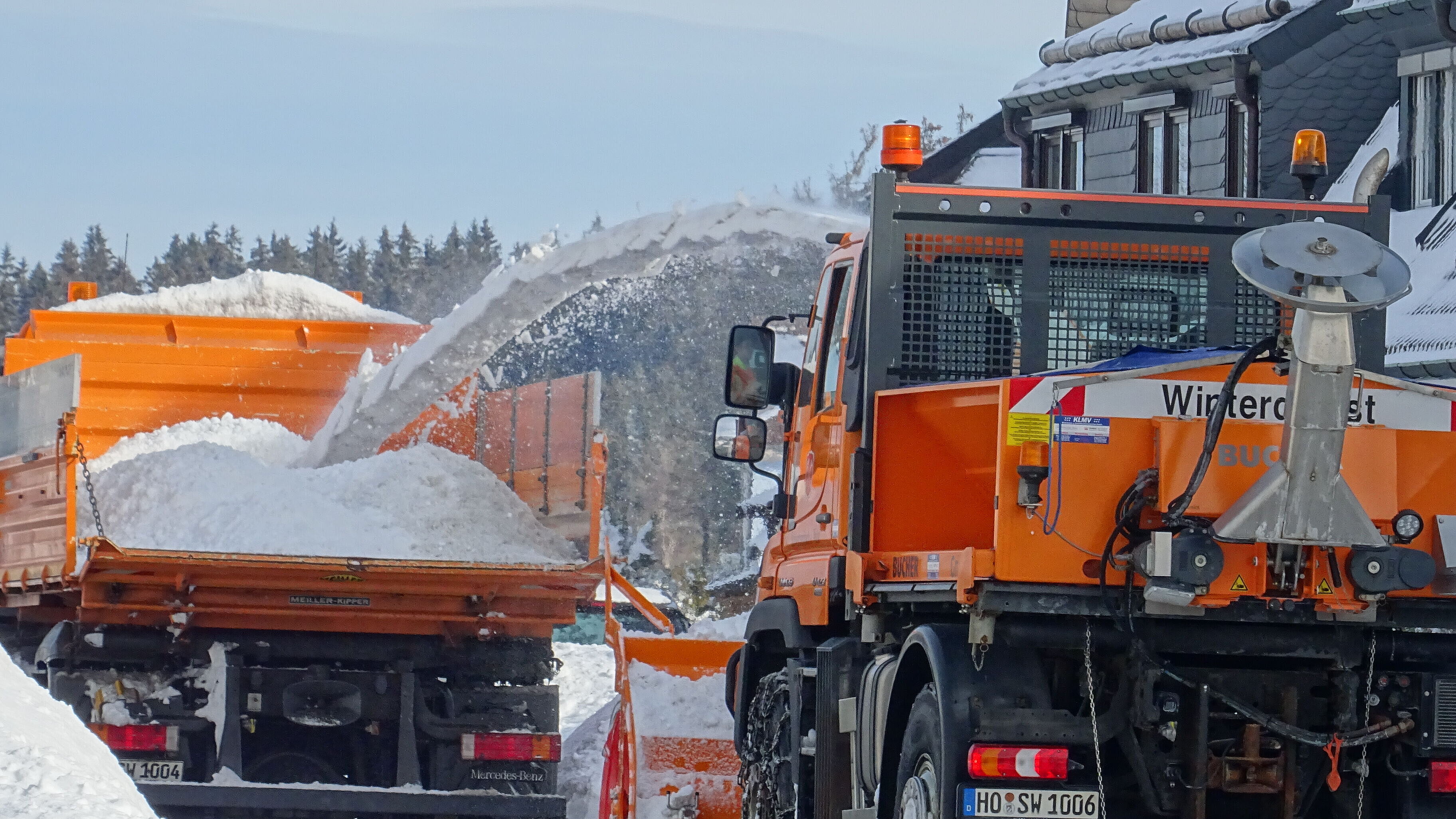 Lkw wird von der Schneefräse mit Schnee für die Abfuhr beladen
